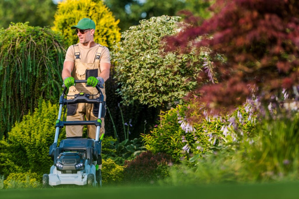 Lawn Caretaker Mowing Grass in a Vibrant Garden During a Sunny Day
